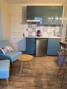 a small kitchen with blue cabinets and a table at Studio jangadi in Reignac