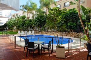 un patio con mesa y sillas junto a una piscina en Aluasun Lago Rojo - Adults recommended, en Torremolinos