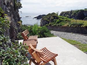2 Stühle auf einem Tisch mit Meerblick in der Unterkunft Casa dos Botes in Santa Cruz das Flores