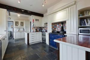 a large kitchen with white cabinets and blue appliances at Old Wharf Cottage - Riverside Living with Pool in Wraysbury