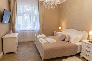 a bedroom with a white bed and a chandelier at Chillinn La Maison Cottage Eger in Eger