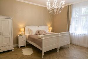 a bedroom with a white bed and a chandelier at Chillinn La Maison Cottage Eger in Eger
