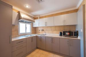 cocina con armarios blancos y microondas en Wahaj Boulevard Hotel Apartmentوهج بوليفارد للشقق الفندقية, en Kuwait