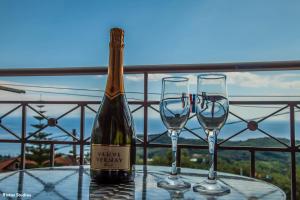 a bottle of wine and two wine glasses on a table at Elena Rista Studios in Parga