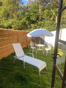 two chairs and a table with an umbrella in a yard at Matha Pousada e Bistrô in Lumiar