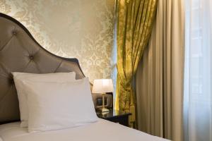 a bed with a white pillow next to a window at Stanhope Hotel by Thon Hotels in Brussels