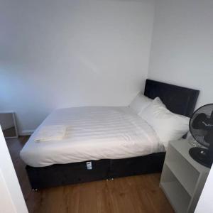 a bed with white sheets and pillows in a room at Beatle Luxy Apartment in Feltham