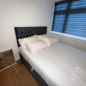 a bed with white pillows in a room with a window at Beatle Luxy Apartment in Feltham