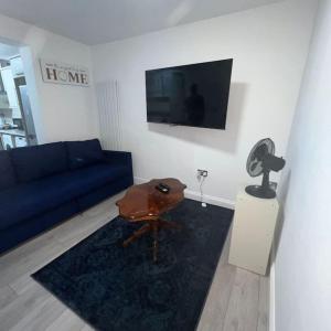 - un salon avec un canapé bleu et une table dans l'établissement Beatle Luxy Apartment, à Feltham