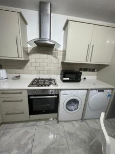 a kitchen with a stove and a washing machine at Beatle Luxy Apartment in Feltham