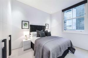 Central Mayfair and Piccadilly Sleeps 6 people في لندن: غرفة نوم بيضاء بها سرير ونافذة