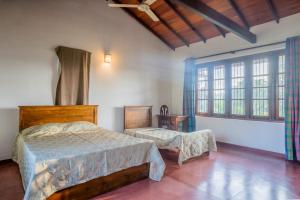 a bedroom with a bed and a chair and windows at The Fields Malabe in Malabe