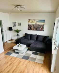 ein Wohnzimmer mit einem schwarzen Sofa und einem Tisch in der Unterkunft Kurstadt Apartment 2ZKB Balkon PKW Stlp-Self-Check-in in Bad Nauheim