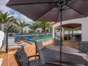 a patio with an umbrella and chairs and a pool at PRIMERA LUXURY HOUSE in Caleta De Fuste