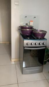 dos ollas púrpuras y sartenes encima de una estufa en PNHouse Anguissa A2, en Yaoundé