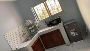 una pequeña cocina con fregadero y ventana en PNHouse Anguissa A2, en Yaoundé
