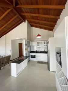 cocina grande con electrodomésticos blancos y techo de madera. en Apartamento Cobertura Ingleses Gr, en Florianópolis