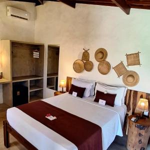 a bedroom with a large bed with hats on the wall at Arataba Hotel Boutique e Bistrô - 150 mts do mar in Pôrto de Pedras