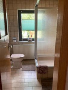 a bathroom with a tub and a toilet and a window at Marja Ferienwohnung in Oberorke