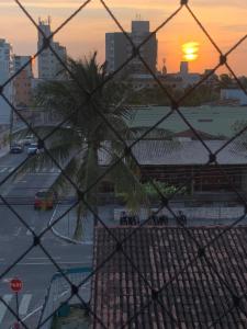 a view of a city from a fence with a palm tree at Apartamento Praia do Morro - Guarapari in Guarapari
