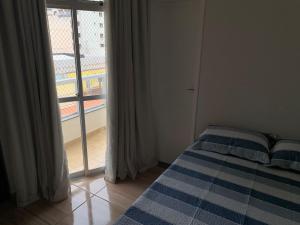 a bedroom with a bed and a large window at Apartamento Praia do Morro - Guarapari in Guarapari