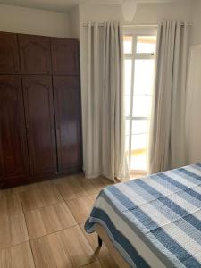 a bedroom with a bed and a large window at Apartamento Praia do Morro - Guarapari in Guarapari