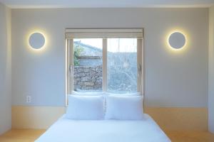 a bedroom with a bed and a large window at Aewol Gilro in Jeju