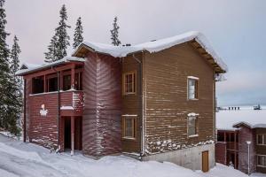 una casa de madera con nieve encima en Viihtyisä lomahuoneisto Rukalla!, en Kuusamo