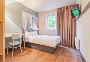 Habitación de hotel con cama, mesa y TV. en B&B HOTEL Mulhouse Ile Napoléon, en Illzach
