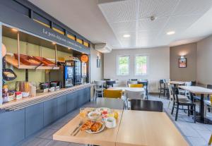 een restaurant met een tafel met eten erop bij B&B HOTEL Mulhouse Ile Napoléon in Illzach