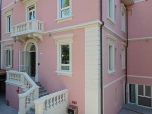 a pink house with stairs and a balcony at Castiglioncello Suite in Castiglioncello