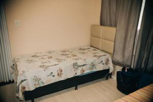 Una cama pequeña en un dormitorio con colcha. en Sitio Silveira Nobre - São Joaquim de Bicas en São Joaquim de Bicas
