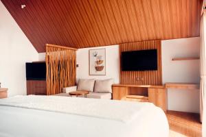 a bedroom with a bed and a couch and a tv at Padi Villas by Aayan in Canggu