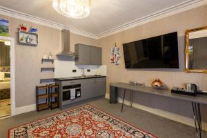 a kitchen with a table and a tv on the wall at THE AMBLESIDE APARTMENTS - Self catering with private kitchen - Best for Location in Ambleside