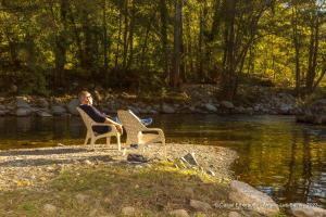 a man sitting in a chair next to a river at Appart'Hotel Castel Emeraude, Charme et Caractère in Amélie-les-Bains-Palalda