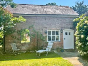 a brick house with two chairs and a white door at Little Barn in Dorchester