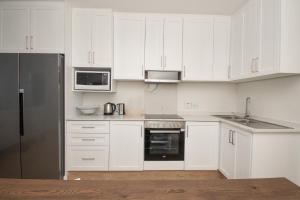 a white kitchen with white cabinets and a black refrigerator at 210 Breakers Resort Umhlanga Rocks in Durban
