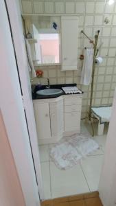 uma pequena casa de banho branca com um lavatório e um espelho. em Hospedagem Domiciliar Alternativa em Balneário Camboriú