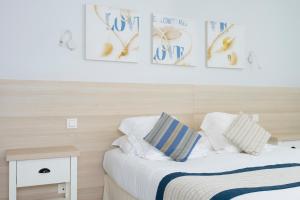 a bedroom with two beds and pictures on the wall at Hotel La Ciotat - A deux pas de l'eau in La Ciotat