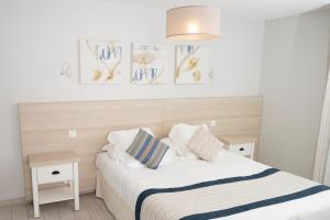 a bedroom with a bed with two night stands and three paintings at Hotel La Ciotat - A deux pas de l'eau in La Ciotat