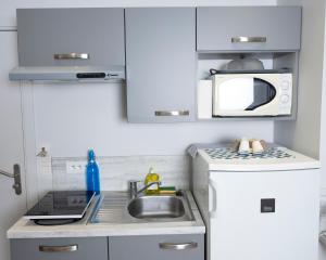 a small kitchen with a sink and a microwave at Hotel La Ciotat - A deux pas de l'eau in La Ciotat