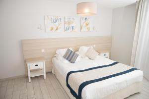 a white bedroom with a bed with two pillows at Hotel La Ciotat - A deux pas de l'eau in La Ciotat