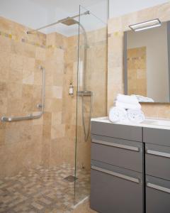 a bathroom with a glass shower and a sink at Hotel La Ciotat - A deux pas de l'eau in La Ciotat