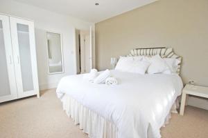 a bedroom with a large white bed with white pillows at Claremont Beach House in Greatstone