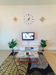 sala de estar con mesa y reloj en la pared en ASFA Homestay Kuching en Kuching