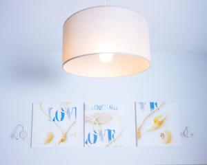 a light fixture hanging on a wall with pictures on it at Hotel La Ciotat - A deux pas de l'eau in La Ciotat