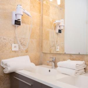 a bathroom with a sink and a mirror and towels at Hotel La Ciotat - A deux pas de l'eau in La Ciotat