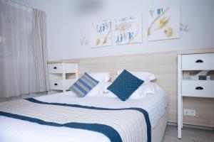 a bedroom with a bed with blue and white pillows at Hotel La Ciotat - A deux pas de l'eau in La Ciotat
