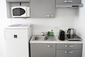 a small kitchen with a sink and a microwave at Hotel La Ciotat - A deux pas de l'eau in La Ciotat