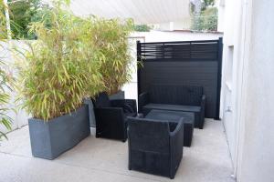 a patio with wicker chairs and potted plants at Hotel La Ciotat - A deux pas de l'eau in La Ciotat